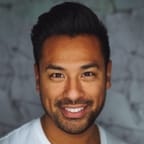 A photo of Thomas in white t-shirt in a grayish background.